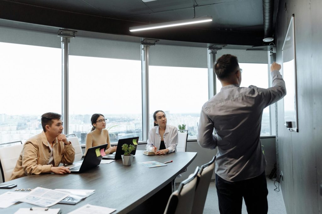 Colleagues in a meeting room discussing a presentation with city views.